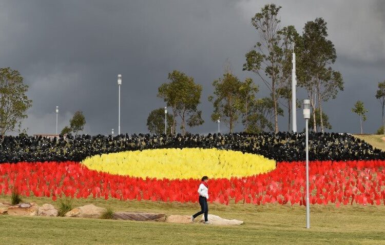 A woman passes a huge art installation called 'Sea of Hands' which consists of thousands of hands in the colours of the Aboriginal flag red, yellow, black. - Part of National Reconciliation Week 2016, the installation is for Australians to reflect on Australias national identity and the place of Aboriginal and Torres Strait Islander histories and cultures in the nations story. (Photo by William WEST / AFP)