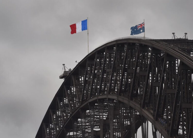 The French flag flies over the Sydney Harbour Bridge on November 15, 2015, as Australians expressed their solidarity with France after a series of bloody attacks. The iconic sails of the Sydney Opera House were also lit in red, white and blue along with the Sydney Town Hall. AFP PHOTO / William WEST (Photo by WILLIAM WEST / AFP)