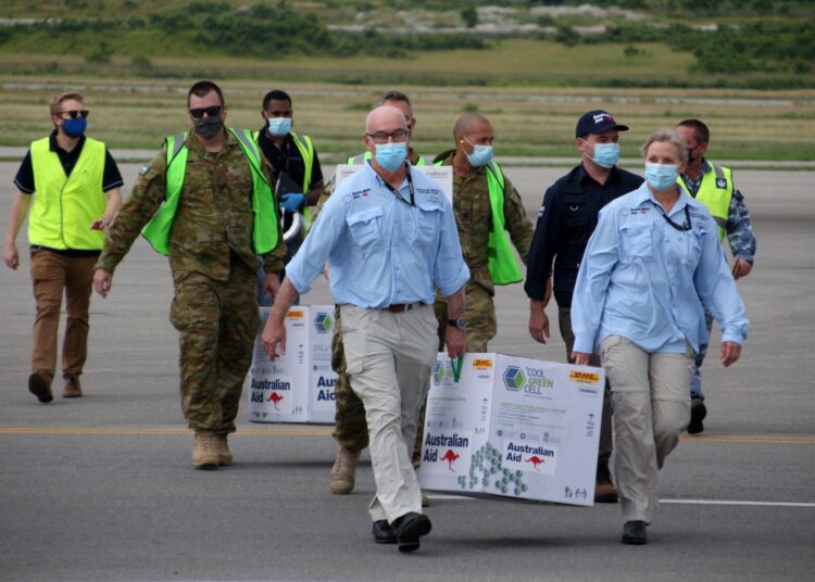Australian officials carry boxes containing some 8,000 initial doses of the AstraZeneca vaccine following their arrival on board a Royal Australian Air Force plane at the Port Moresby international airport on March 23, 2021, as Papua New Guinea raced to quell a Covid-19 surge overwhelming its fragile health system. (Photo by Andrew KUTAN / AFP)