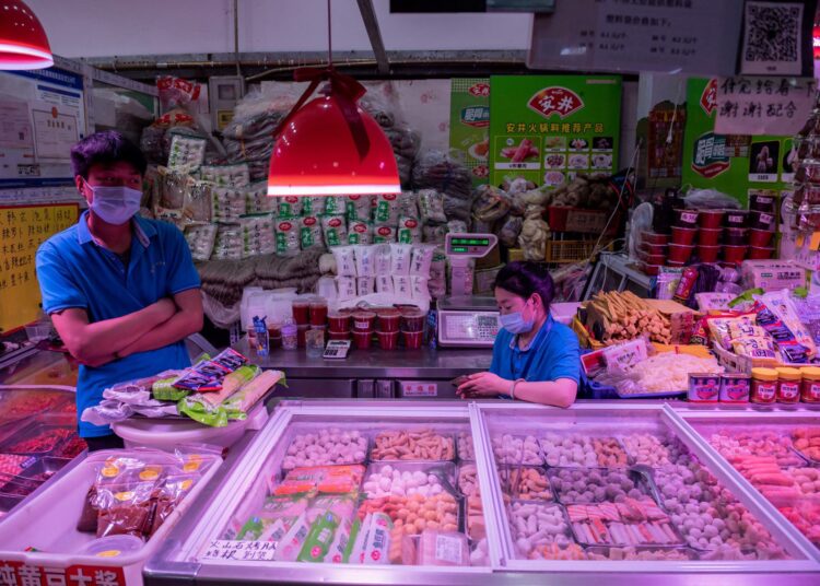 (FILES) This file photo taken on June 20, 2020 shows vendors waiting for customers at their stall selling frozen meat and seafood balls at a market in Beijing. - The chances that Covid-19 emerged in Wuhan because of imported frozen food are "very low", international health experts said March 29, 2021, casting doubt on one of the main theories China has embraced for the cause of the first coronavirus outbreak in late 2019. (Photo by NICOLAS ASFOURI / AFP)