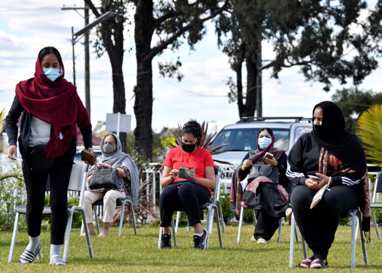 This picture taken on August 26, 2021, shows members of the local Sikh community waiting for their turn to get Pfizer vaccine dose inside a Glenwood Sikh Temple in Sydney. (Photo by Saeed KHAN / AFP) / TO GO WITH: HEALTH-VIRUS-AUSTRALIA-MINORITIES, FOCUS BY ANDREW LEESON, WITH NAJMA SAMBUL IN MELBOURNE - TO GO WITH: Health-virus-Australia-minorities, FOCUS by Andrew LEESON, with Najma Sambul in Melbourne