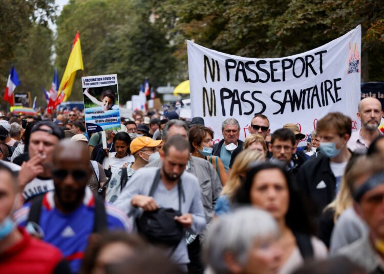 Demonstrators march during a protest called by Gilets Jaunes (yellow vest) and Citoyens en colere movements against the compulsory Covid-19 vaccination for certain workers, and the mandatory use of the health pass called for by the French government to access most public spaces, on De Villiers Avenue in Paris on September 11, 2021. - The sign reads 'Neither passport nor health pass'. (Photo by Thomas SAMSON / AFP)