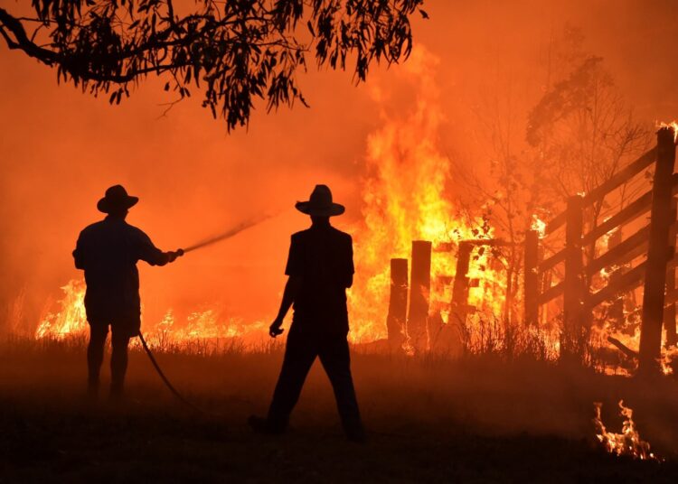 (FILES) This file photo taken on November 12, 2019 shows residents defending a property from a bushfire at Hillsville near Taree, 350km north of Sydney. - Australia's unprecedented 2019-2020 bushfires were "clearly" fuelled by climate change, according to the findings of a government inquiry released on August 25, 2020. (Photo by Peter PARKS / AFP)