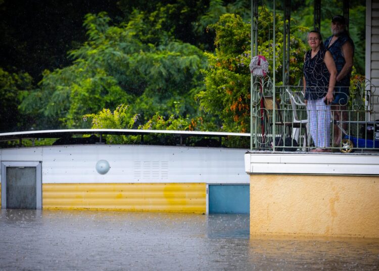 Residents look at floodwaters from the balcony of their home in West Ipswich, Australia's Queensland state on February 26, 2022. (Photo by Patrick HAMILTON / AFP)