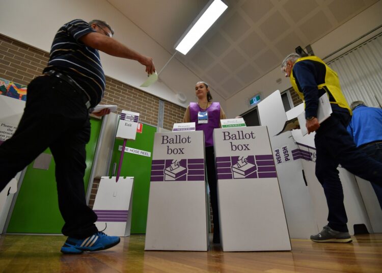 A voter drops his ballot paper into the ballot box at the Lilly Pilly polling booth during the Australia's general election in Sydney on May 18, 2019. (Photo by Saeed KHAN / AFP)