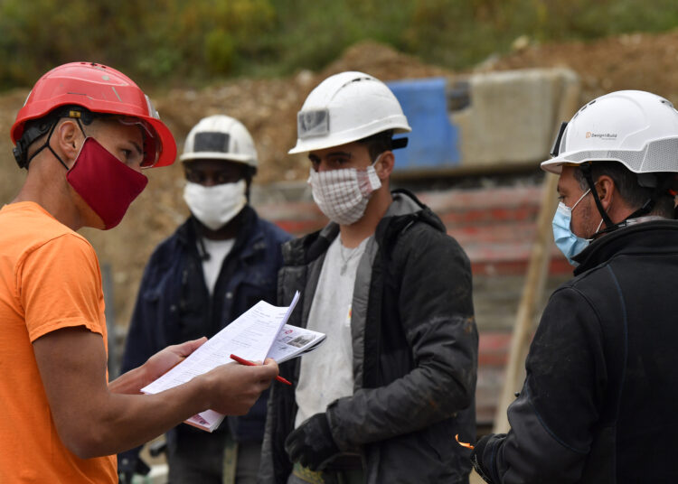 Construction workers wearing protective masks work on April 28, 2020 at the parking construction site in Chambery , eastern France. Construction companies reviewed a large part of the production processes due to a lockdown in France aimed at curbing the spread of the COVID-19 pandemic, the novel coronavirus.     AFP PHOTO/PHILIPPE DESMAZES