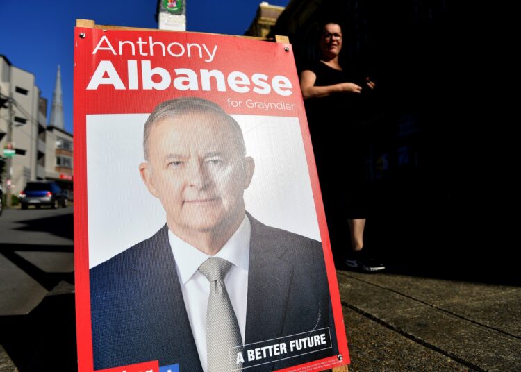 A resident walks past a pre-polling station as a poster of Australian Opposition Leader Anthony Albanese is seen, in the Marrickville suburb of Sydney on May 17, 2022, as Australians go to the polls on May 21 to decide who will run the country for the next three years. (Photo by Saeed KHAN / AFP)