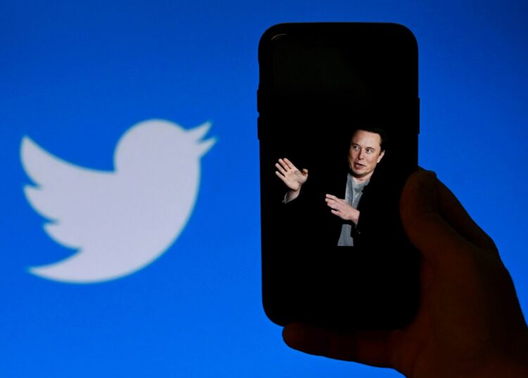 (FILES) In this file illustration photo taken on October 4, 2022, a phone screen displays a photo of Elon Musk with the Twitter logo shown in the background in Washington, DC. - The New York Stock Exchange did not permit trading on Twitter on October 28, 2022 after Elon Musk completed a $44 billion takeover of the social media platform. Twitter was listed among the companies experiencing a "trading halt," according to an NYSE notice that said the merger was "effective." (Photo by OLIVIER DOULIERY / AFP) / NO USE AFTER NOVEMBER 27, 2022 14:15:05 GMT