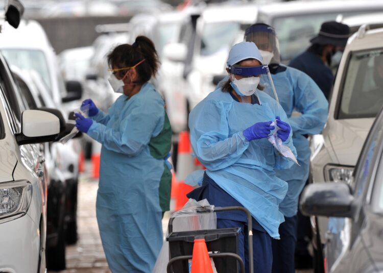 Health workers conduct PCR tests at the St Vincent's Bondi Beach COVID-19 drive through testing clinic on December 22, 2021 in Sydney, as the number of COVID-19 cases keeps on the rise across the New South Wales state ahead of the Christmas festivities. (Photo by MUHAMMAD FAROOQ / AFP)