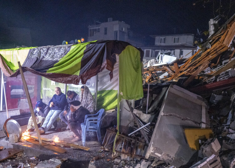 People take rest next to bonfire in the rubble in Hatay, after a 7.8-magnitude earthquake struck the country's southeast on February 6, 2023. - A major 7.8-magnitude earthquake struck Turkey and Syria, killing more than 3,000 people and flattening thousands of buildings as rescuers dug with bare hands for survivors. (Photo by BULENT KILIC / AFP)