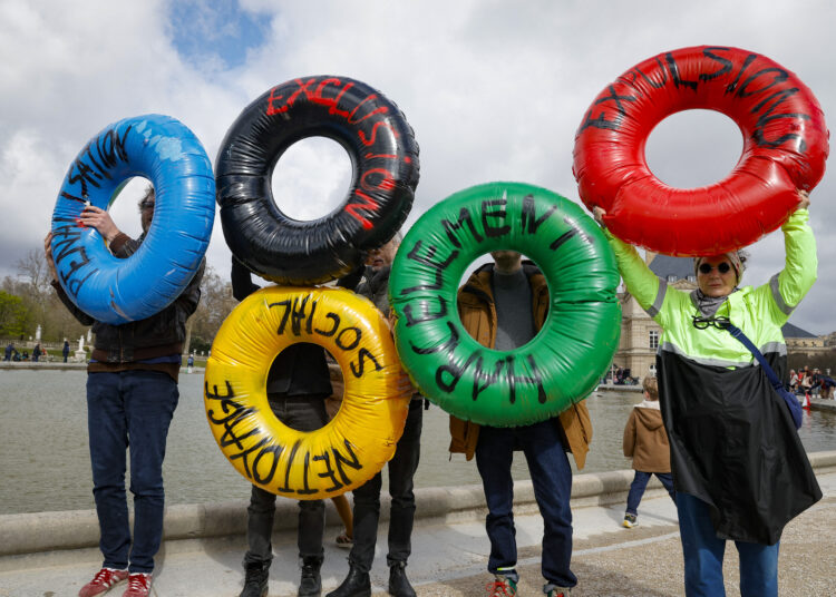 Activists of the collective "Le revers de la medaille" (the flip side of the coin) show inflatable buoys at the Jardin du Luxembourg in Paris during a demonstration to draw attention to social inequality exacerbated by the upcoming Paris 2024 Olympic Games, on March 24, 2024. - In what they refer to as "social cleansing" of the streets of Paris, the collective alleges that the Olympic games will negatively impact those in need, including the homeless or people facing food insecurity. The buoys read (L to R)"Penalisation / Exclusion / Social cleansing / Harassment / Expulsion" (Photo by Geoffroy VAN DER HASSELT / AFP)