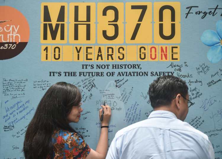 A woman writes a message during an event held by relatives of the passengers and supporters to mark the 10th year since the Malaysia Airlines flight MH370 carrying 239 people disappeared from radar screens on March 8, 2014 while en route from Kuala Lumpur to Beijing, in Subang Jaya on March 3, 2024. (Photo by Arif Kartono / AFP)