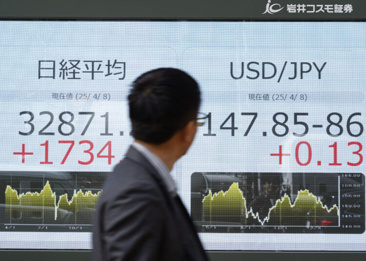 A man looks at an electronic board showing the numbers of the Nikkei Stock Average (L) on the Tokyo Stock Exchange and a USD/JPY foreign exchagne board (R) along a street in Tokyo on April 8, 2025. Tokyo's Nikkei index jumped nearly six percent in early trade on April 8 after plunging an eye-watering 7.8 percent the previous day, as US tariffs fuel market volatility. (Photo by Kazuhiro NOGI / AFP)