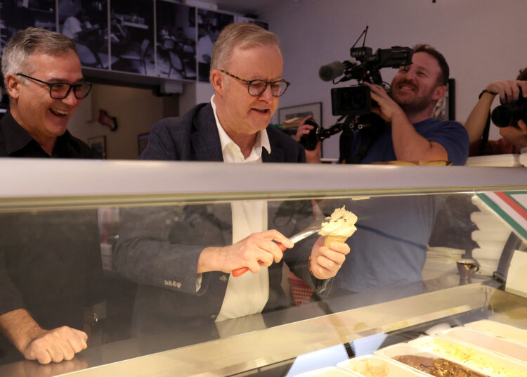Australia's re-elected Prime Minister Anthony Albanese scoops an ice cream for a customer during a visit to a cafe in Sydney on May 4, 2025, following his partys decisive victory in the federal election. (Photo by DAVID GRAY / AFP)