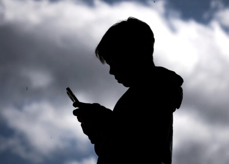 This photo taken on October 24, 2025 shows a 14-year-old boy posing at his home near Gosford as he looks at social media on his mobile phone. Australia will ban young teenagers from social media on December 10, 2025, launching a world-first crackdown designed to unglue children from addictive scrolling on the likes of Facebook, Instagram and TikTok. (Photo by David GRAY / AFP)