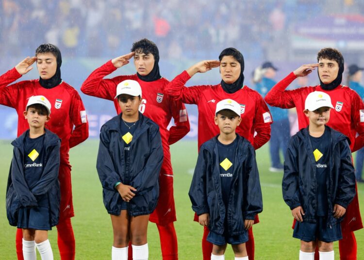 Iran's players salute during the national anthem before the AFC Women's Asian Cup Australia 2026 football match between Iran and Philippines in Gold Coast on March 8, 2026. The son of the late shah urged Canberra on March 9 to protect the Iranian women's football team, who were branded "wartime traitors" after refusing to sing the national anthem while playing in Australia. (Photo by AFP) / -- IMAGE RESTRICTED TO EDITORIAL USE - STRICTLY NO COMMERCIAL USE --